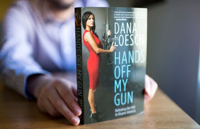 A man reads "Hands off my gun" written by the NRA Spokeperson Dana Loesch in Washington DC on February 8, 2018. Each time there's another mass shooting in the United States, Shannon Watts and Dana Loesch take to Twitter on opposite ends of the gun debate. Watts, founder of Moms Demand Action for Gun Sense in America, makes the arguments for stricter gun control in a country with 33,000 gun-related deaths a year. Loesch, spokeswoman for the National Rifle Association (NRA) and a conservative radio host, lays out the case for why Americans need weapons for self-defense. The two women have become two of the most prominent public faces of the gun control debate with hundreds of thousands of followers across the United States. / AFP PHOTO / Eric BARADAT (Photo credit should read ERIC BARADAT/AFP via Getty Images)