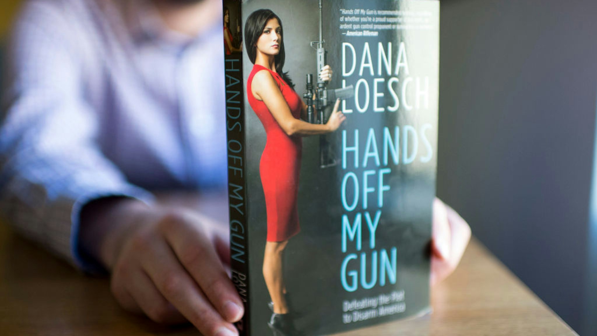 A man reads "Hands off my gun" written by the NRA Spokeperson Dana Loesch in Washington DC on February 8, 2018. Each time there's another mass shooting in the United States, Shannon Watts and Dana Loesch take to Twitter on opposite ends of the gun debate. Watts, founder of Moms Demand Action for Gun Sense in America, makes the arguments for stricter gun control in a country with 33,000 gun-related deaths a year. Loesch, spokeswoman for the National Rifle Association (NRA) and a conservative radio host, lays out the case for why Americans need weapons for self-defense. The two women have become two of the most prominent public faces of the gun control debate with hundreds of thousands of followers across the United States. / AFP PHOTO / Eric BARADAT (Photo credit should read ERIC BARADAT/AFP via Getty Images)