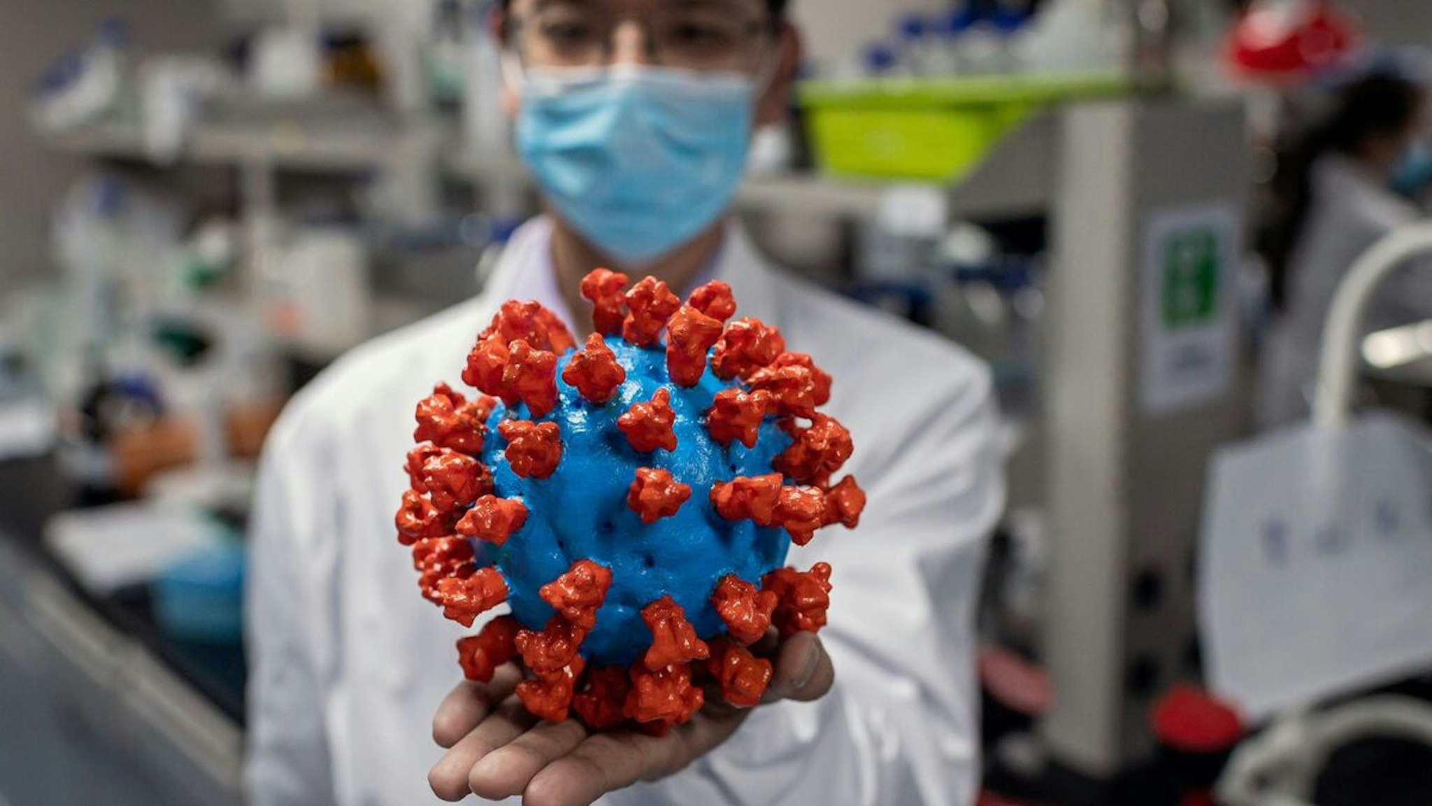 TOPSHOT - In this picture taken on April 29, 2020, an engineer shows a plastic model of the COVID-19 coronavirus at the Quality Control Laboratory at the Sinovac Biotech facilities in Beijing. - Sinovac Biotech, which is conducting one of the four clinical trials that have been authorised in China, has claimed great progress in its research and promising results among monkeys. (Photo by NICOLAS ASFOURI / AFP) / TO GO WITH Health-virus-China-vaccine,FOCUS by Patrick Baert