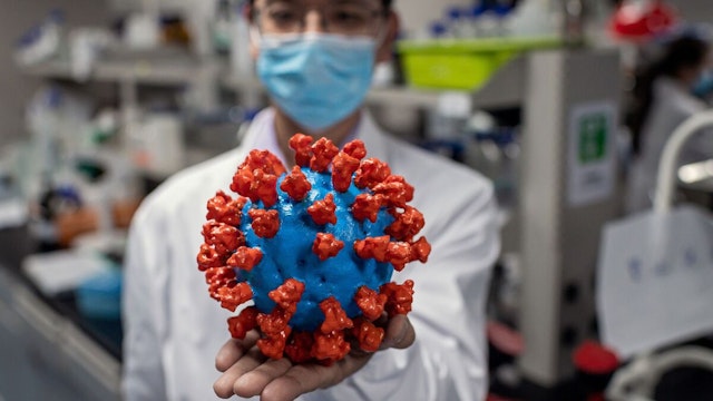 TOPSHOT - In this picture taken on April 29, 2020, an engineer shows a plastic model of the COVID-19 coronavirus at the Quality Control Laboratory at the Sinovac Biotech facilities in Beijing. - Sinovac Biotech, which is conducting one of the four clinical trials that have been authorised in China, has claimed great progress in its research and promising results among monkeys. (Photo by NICOLAS ASFOURI / AFP) / TO GO WITH Health-virus-China-vaccine,FOCUS by Patrick Baert