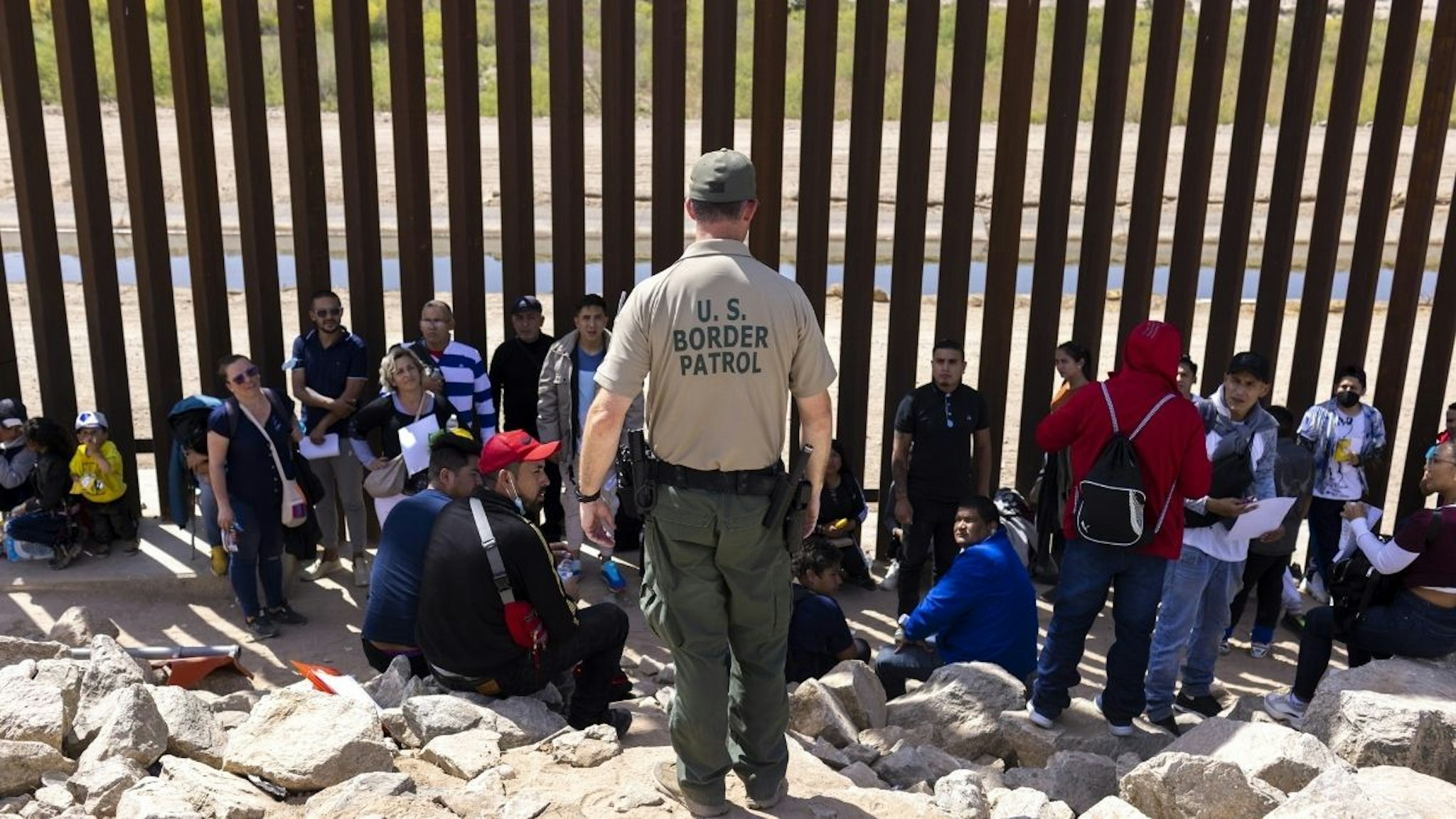 A U.S. Border Patrol agents speaks with migrants seeking asylum after crossing the Mexico and U.S. border in Yuma, Arizona, U.S. on Tuesday, May 3, 2022.