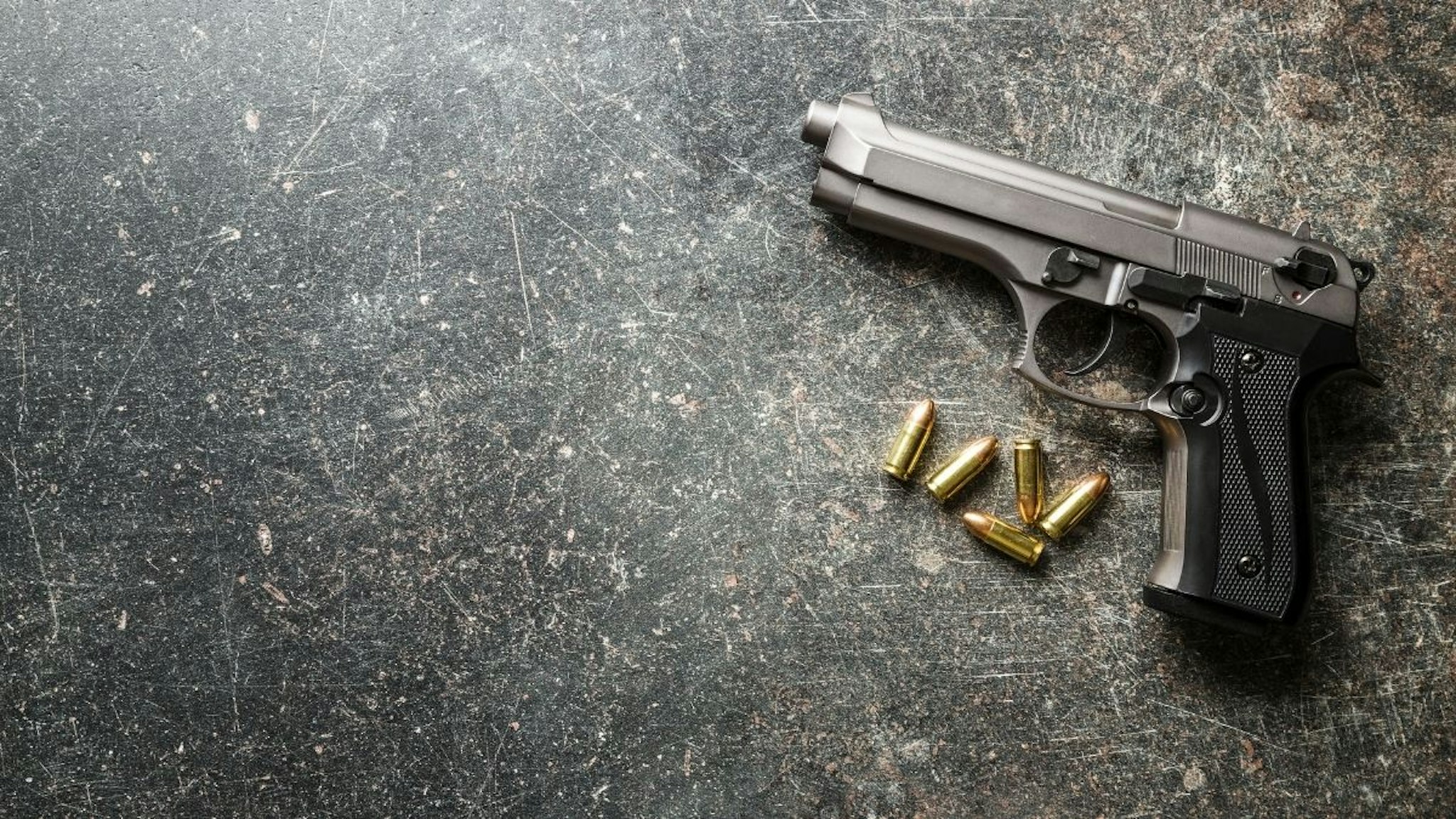 9mm pistol bullets and handgun on black table.