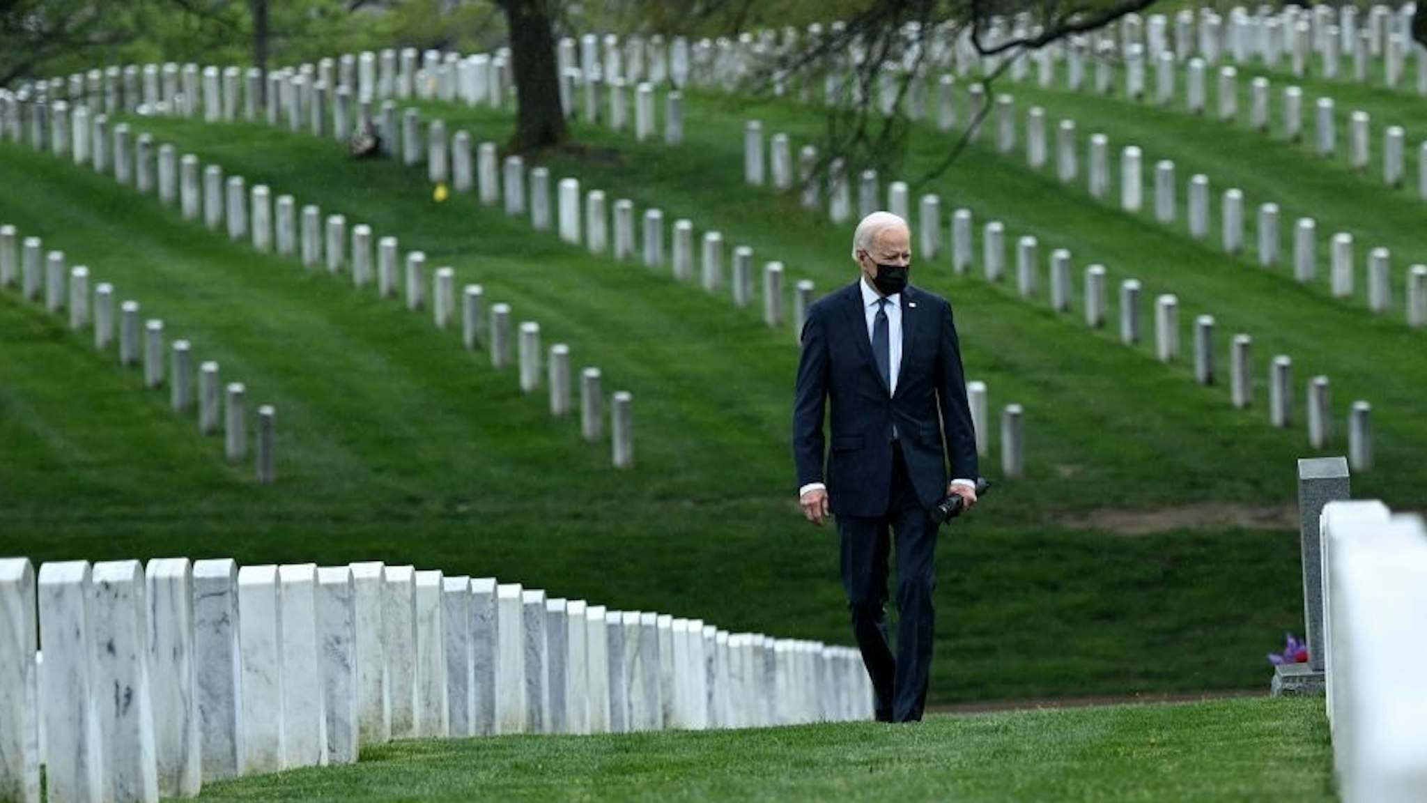TOPSHOT - US President Joe Biden walks through Arlington National cemetary to honor fallen veterans of the Afghan conflict in Arlington, Virginia on April 14, 2021. - President Joe Biden announced it's "time to end" America's longest war with the unconditional withdrawal of troops from Afghanistan, where they have spent two decades in a bloody, largely fruitless battle against the Taliban. (Photo by Brendan SMIALOWSKI / AFP) (Photo by