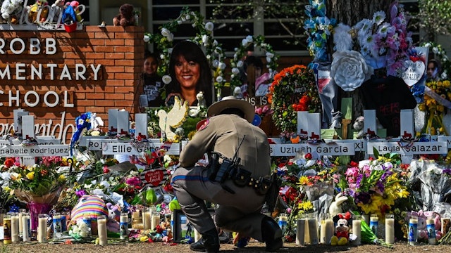 A police officer clears the makeshift memorial before the visit of US President Joe Biden at Robb Elementary School in Uvalde, Texas, on May 29, 2022. - The President and First Lady are in Uvalde to pay their respects following a school shooting. (Photo by CHANDAN KHANNA / AFP) (Photo by CHANDAN KHANNA/AFP via Getty Images)