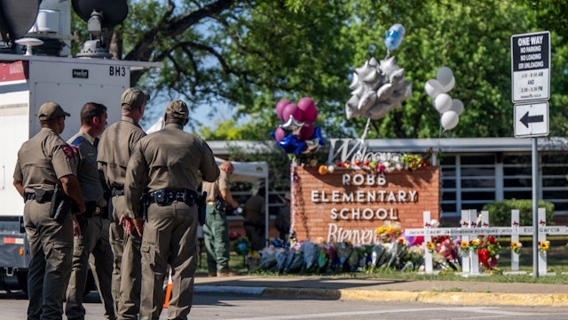 UVALDE, TEXAS - MAY 26: Law enforcement officers stand looking at a memorial following a mass shooting at Robb Elementary School on May 26, 2022 in Uvalde, Texas. According to reports, 19 students and 2 adults were killed, with the gunman fatally shot by law enforcement. (Photo by Brandon Bell/Getty Images)