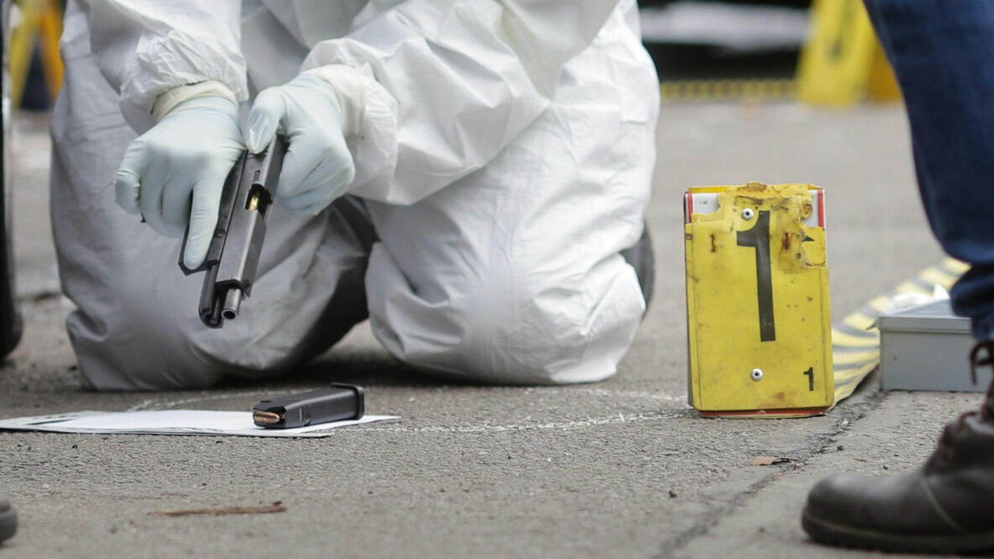 Criminal investigators inspect a handgun at a crime scene