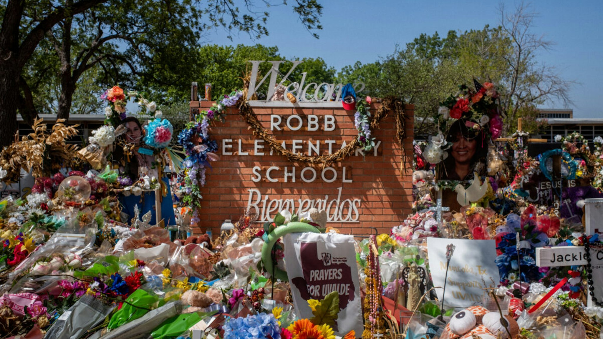 The Robb Elementary School sign is seen covered in flowers and gifts on June 17, 2022 in Uvalde, Texas. Committees have begun inviting testimony from law enforcement authorities, family members and witnesses regarding the mass shooting at Robb Elementary School which killed 19 children and two adults