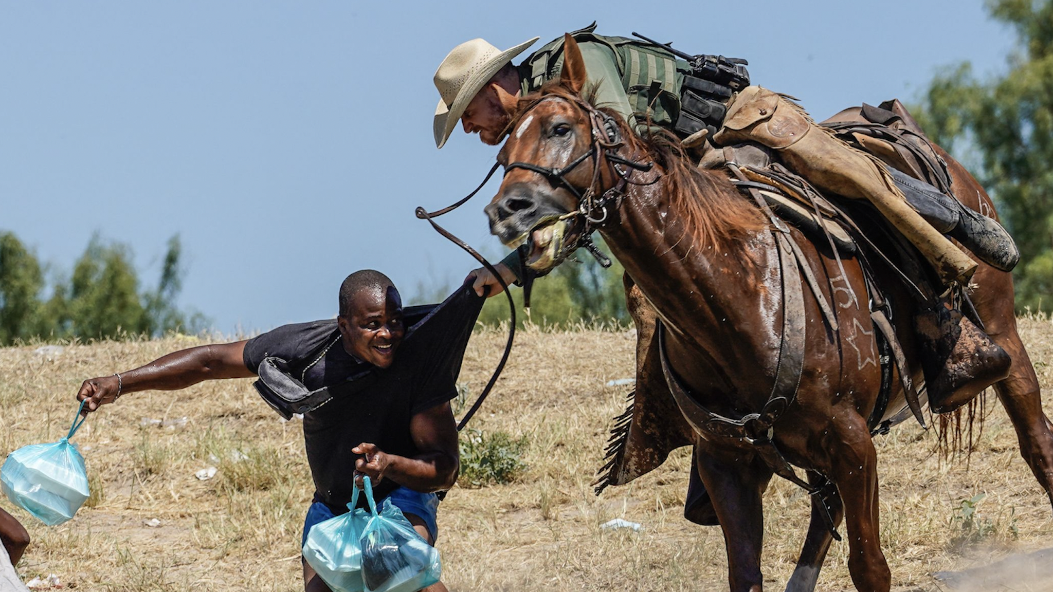 TOPSHOT - A United States Border Patrol agent on horseback tries to stop a Haitian migrant from entering an encampment on the banks of the Rio Grande near the Acuna Del Rio International Bridge in Del Rio, Texas on September 19, 2021.