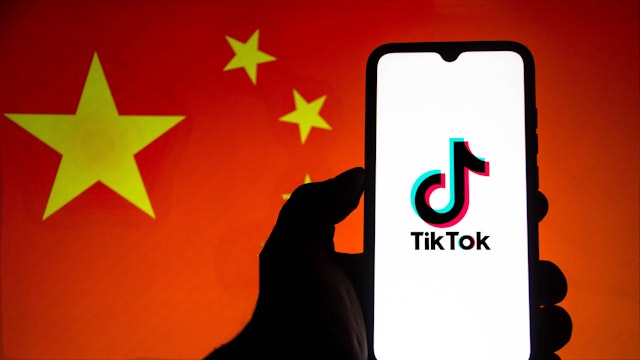 BRAZIL - 2021/02/18: In this photo illustration the TikTok logo seen displayed on a smartphone screen with the flag of China In the background.