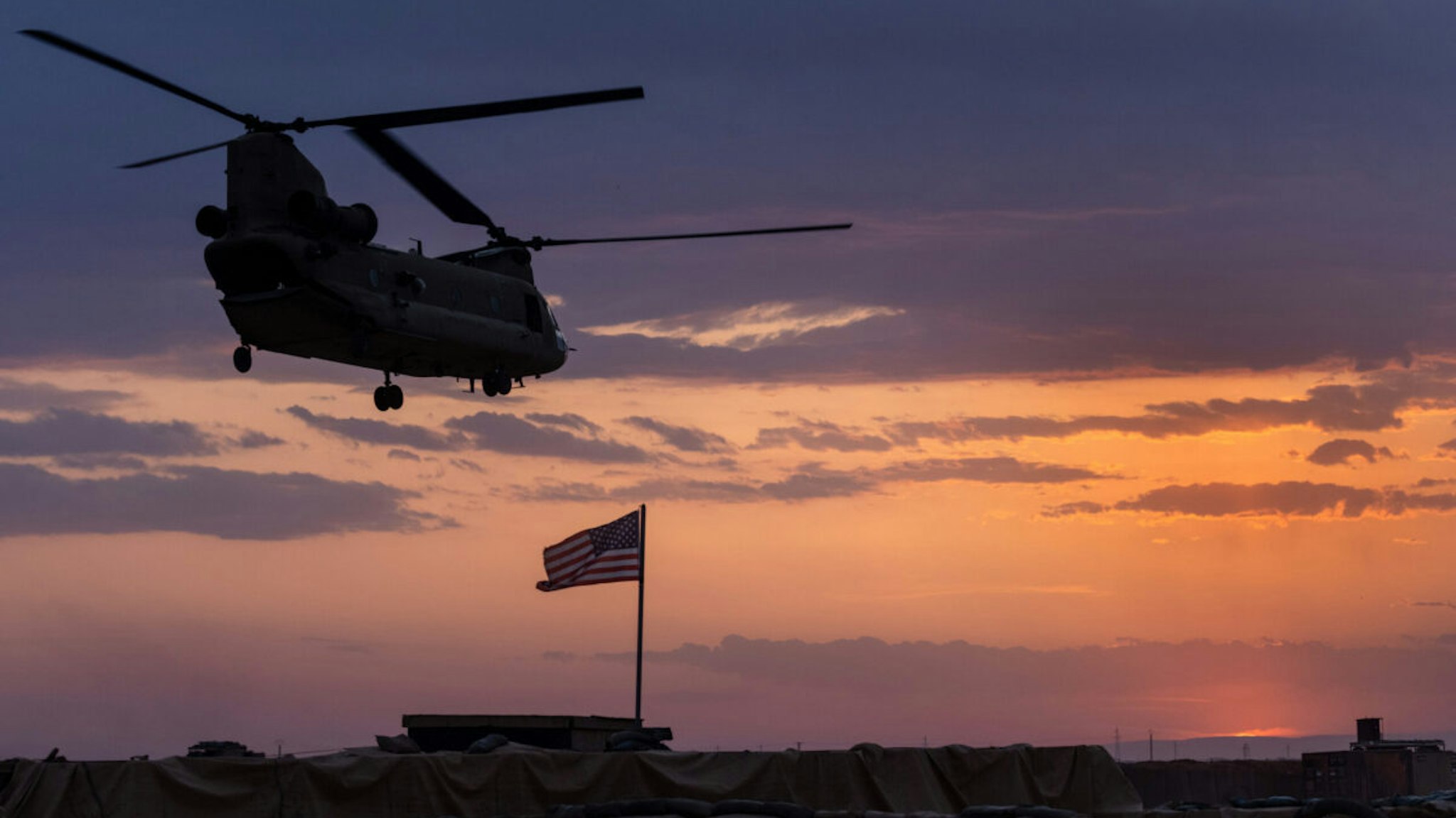 A U.S. Army CH-47 Chinook helicopter takes off at sunset while transporting American troops out of a remote combat outpost known as RLZ on May 25, 2021 near the Turkish border in northeastern Syria