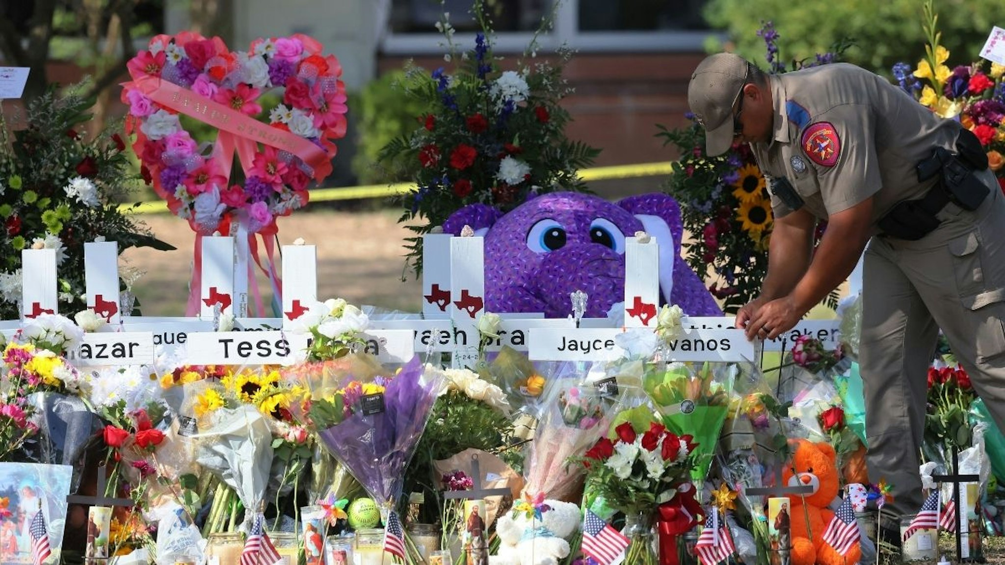 A Texas Highway Patrol Trooper places an item at a memorial for victims of Tuesday's mass shooting at Robb Elementary School on May 27, 2022 in Uvalde, Texas.