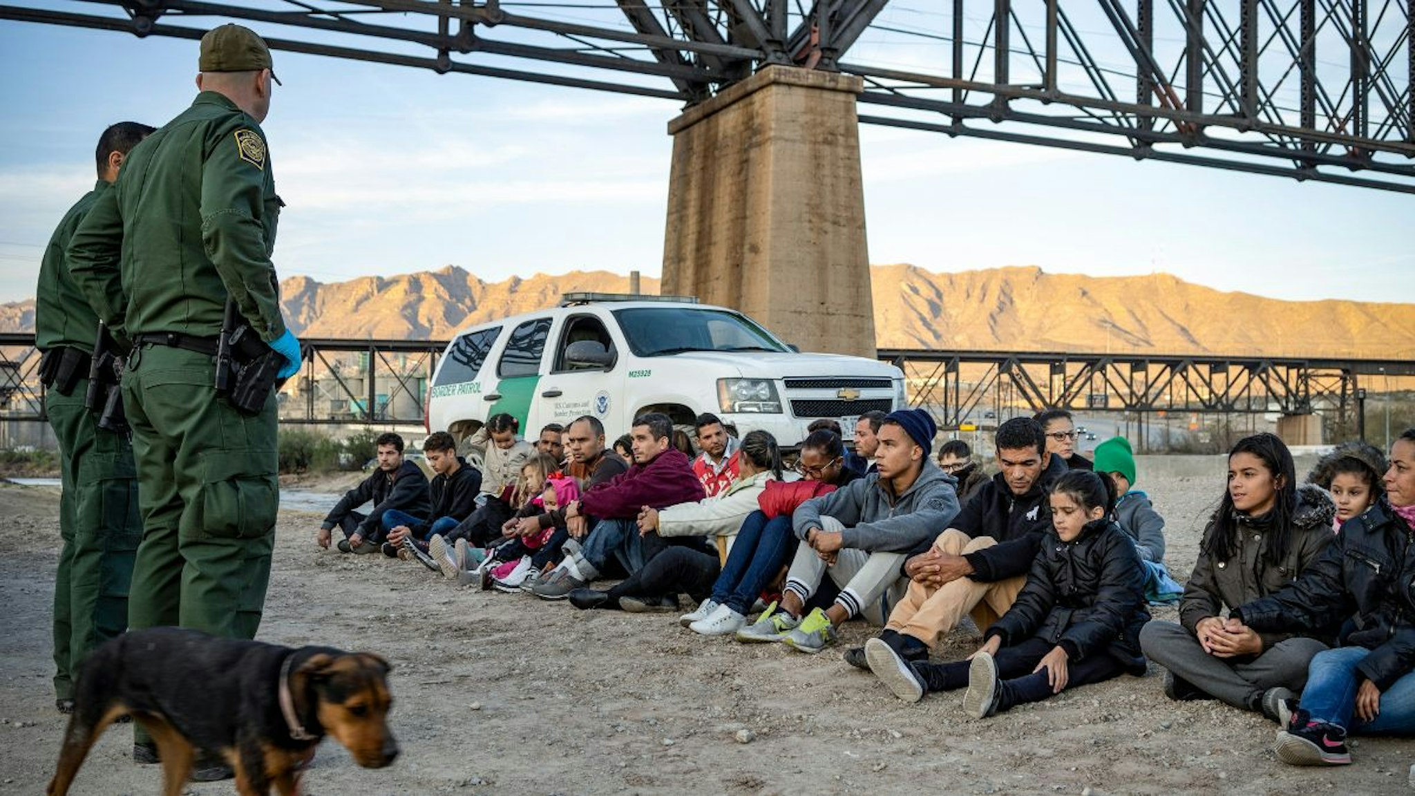 A group of about 30 Brazilian migrants, who had just crossed the border, sit on the ground near US Border Patrol agents, on the property of Jeff Allen, who used to run a brick factory near Mt. Christo Rey on the US-Mexico border in Sunland Park, New Mexico on March 20, 2019.