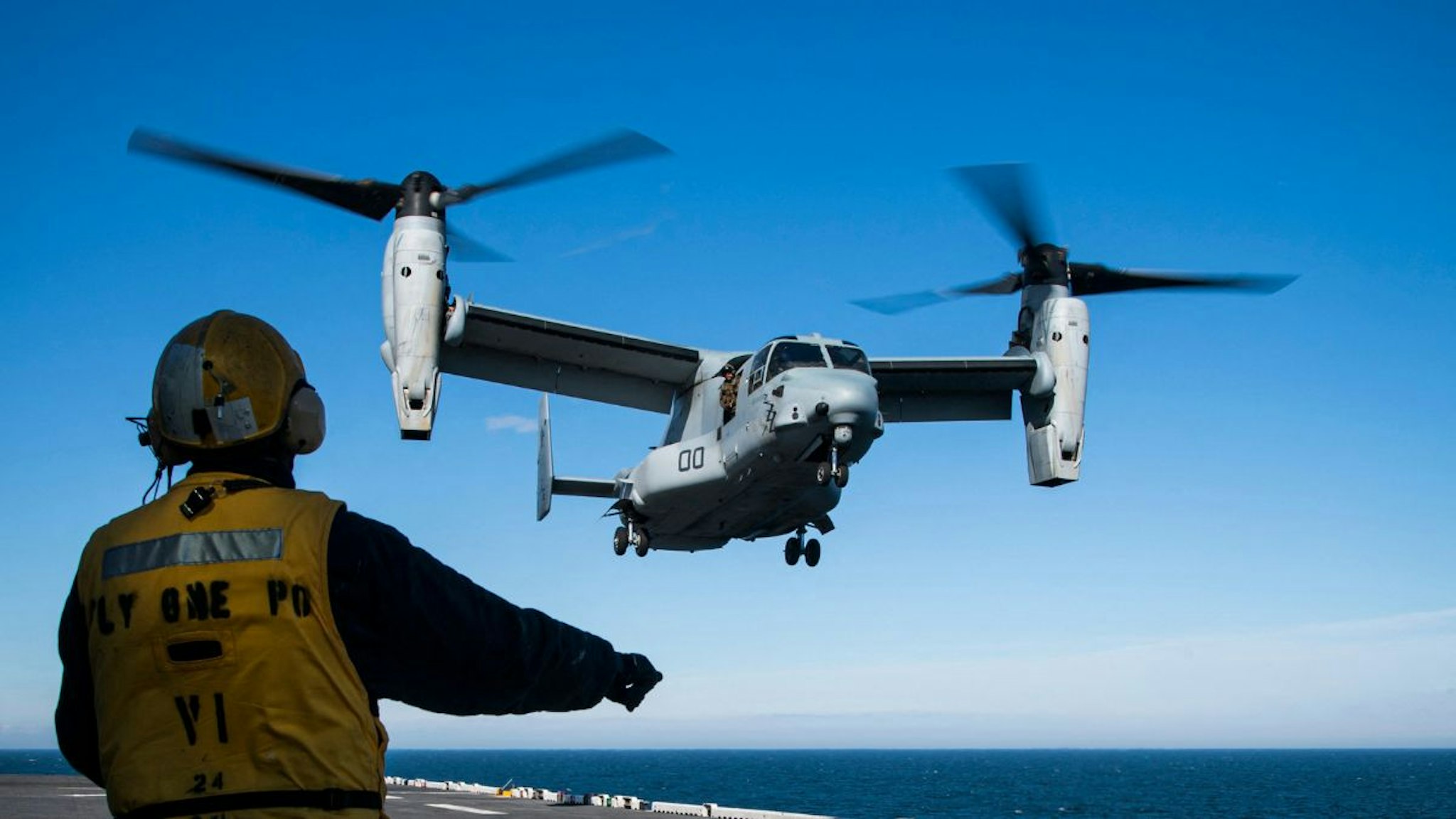 Aviation Boatswains Mate signals to the pilots of a MV-22 Osprey assault support aircraft, assigned to the 22nd Marine Expeditionary Unit, as it approaches to land on the flight deck of the Wasp-class amphibious assault ship USS Kearsarge (LHD 3) on June 8, 2022, during the BALTOPS 22 Exercise in the Baltic Sea.