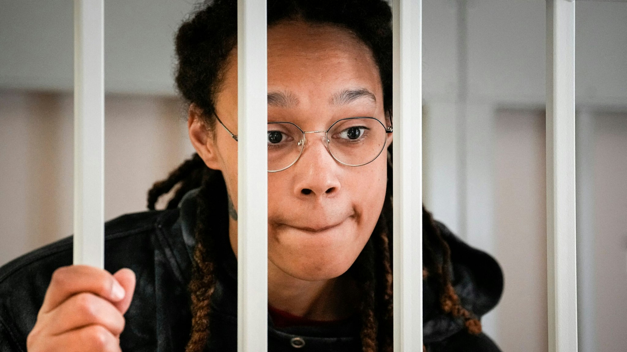 US WNBA basketball superstar Brittney Griner reacts inside a defendants' cage before a hearing at the Khimki Court, outside Moscow on July 26, 2022. - Griner, a two-time Olympic gold medallist and WNBA champion, was detained at Moscow airport in February on charges of carrying in her luggage vape cartridges with cannabis oil, which could carry a 10-year prison sentence.