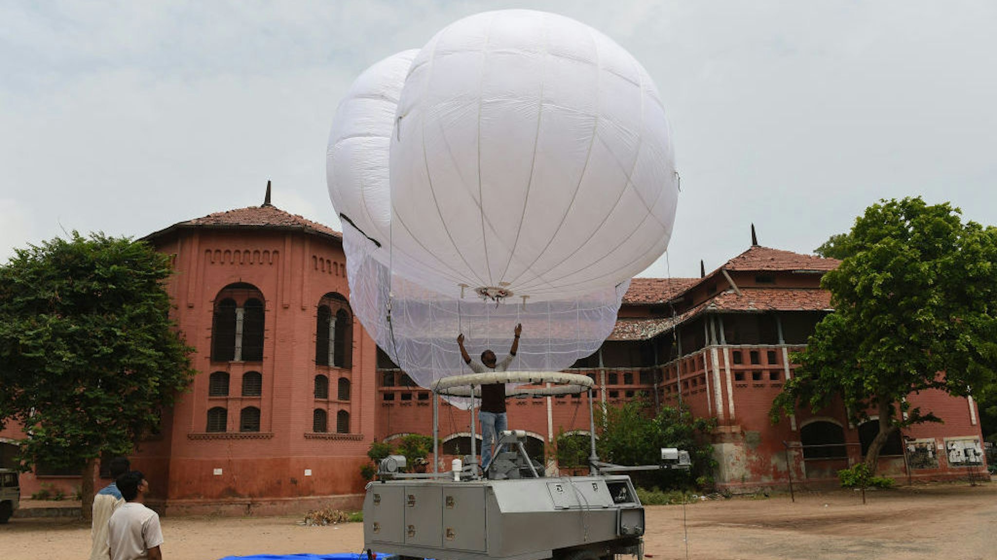 Indian technicians from Tata Power and Indian Border Security Force (BSF) assemble an Israeli-made surveillance Aerostat Balloon in Ahmedabad on July 13, 2018. - The Aerostat Balloon, which reaches a height of 250 metres and provides surveillance over a 5km radius, is set to be used in Ahmedabad for the annual religious Rath Yatra chariot procession on July 14, backed by thousands of Gujarati police and paramilitary security personnel. (Photo by SAM PANTHAKY / AFP) (Photo credit should read SAM PANTHAKY/AFP via Getty Images)