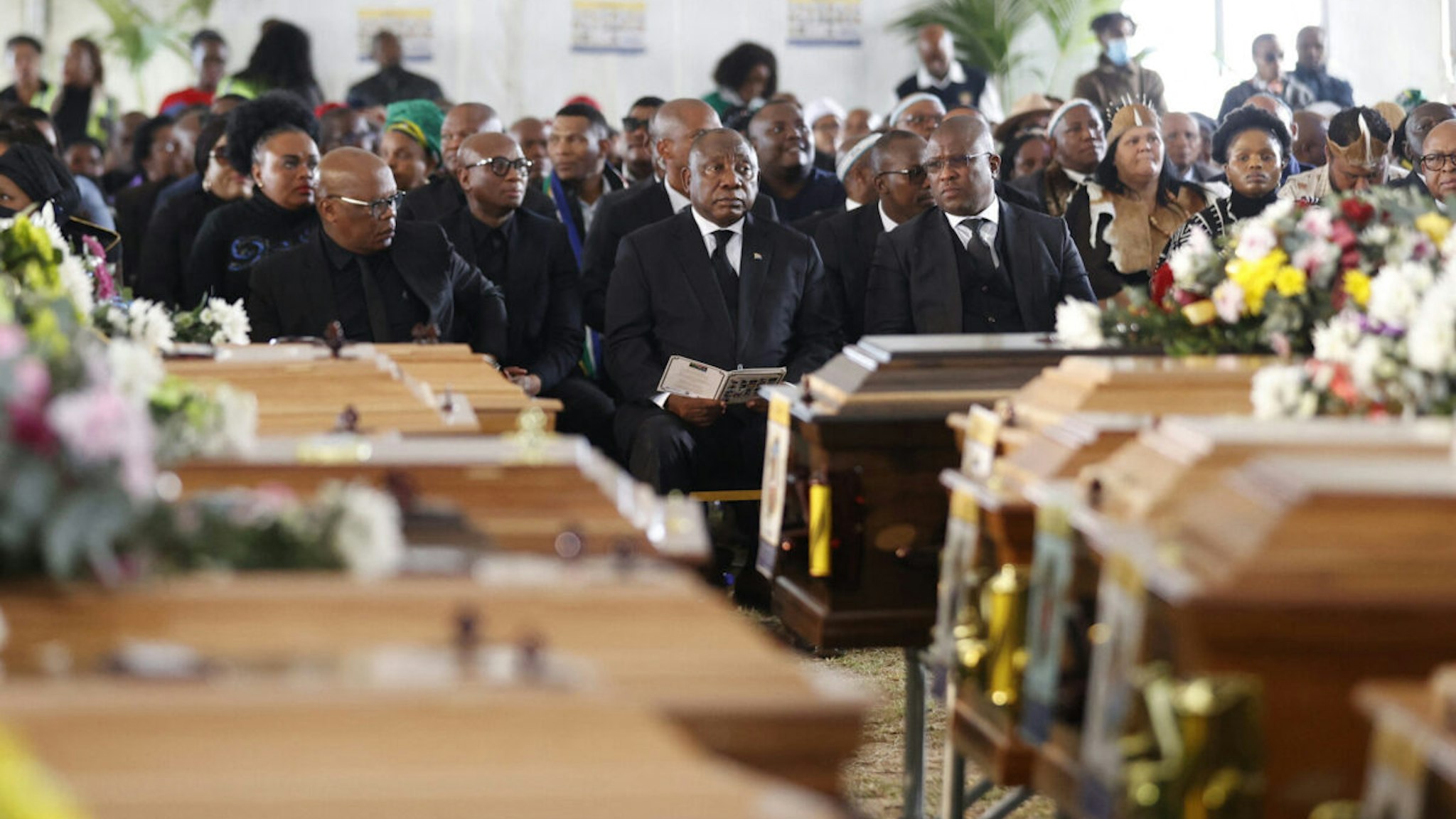 South African President Cyril Ramaphosa (C) looks on during a symbolic mass memorial service in East London on July 6, 2022, after 21 people, mostly teens, died in unclear circumstances at a township tavern last month, in an incident that shocked South Africa. (Photo by Phill Magakoe / AFP) (Photo by PHILL MAGAKOE/AFP via Getty Images)