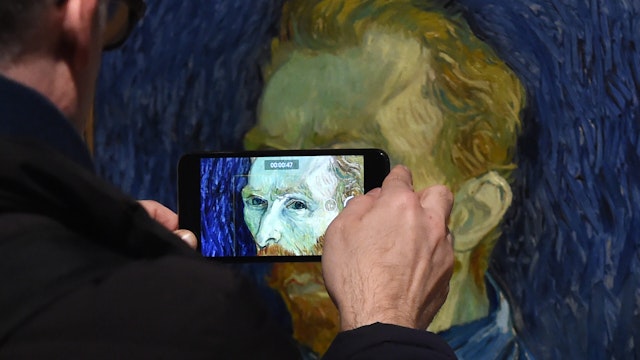 LONDON, ENGLAND - MARCH 25: A man takes a close-up photograph of a self portrait painting by famous Dutch artist Vincent van Gogh at the EY Exhibition: Van Gogh and Britain press day which opens at Tate Britain on March 25, 2019 in London, United Kingdom.