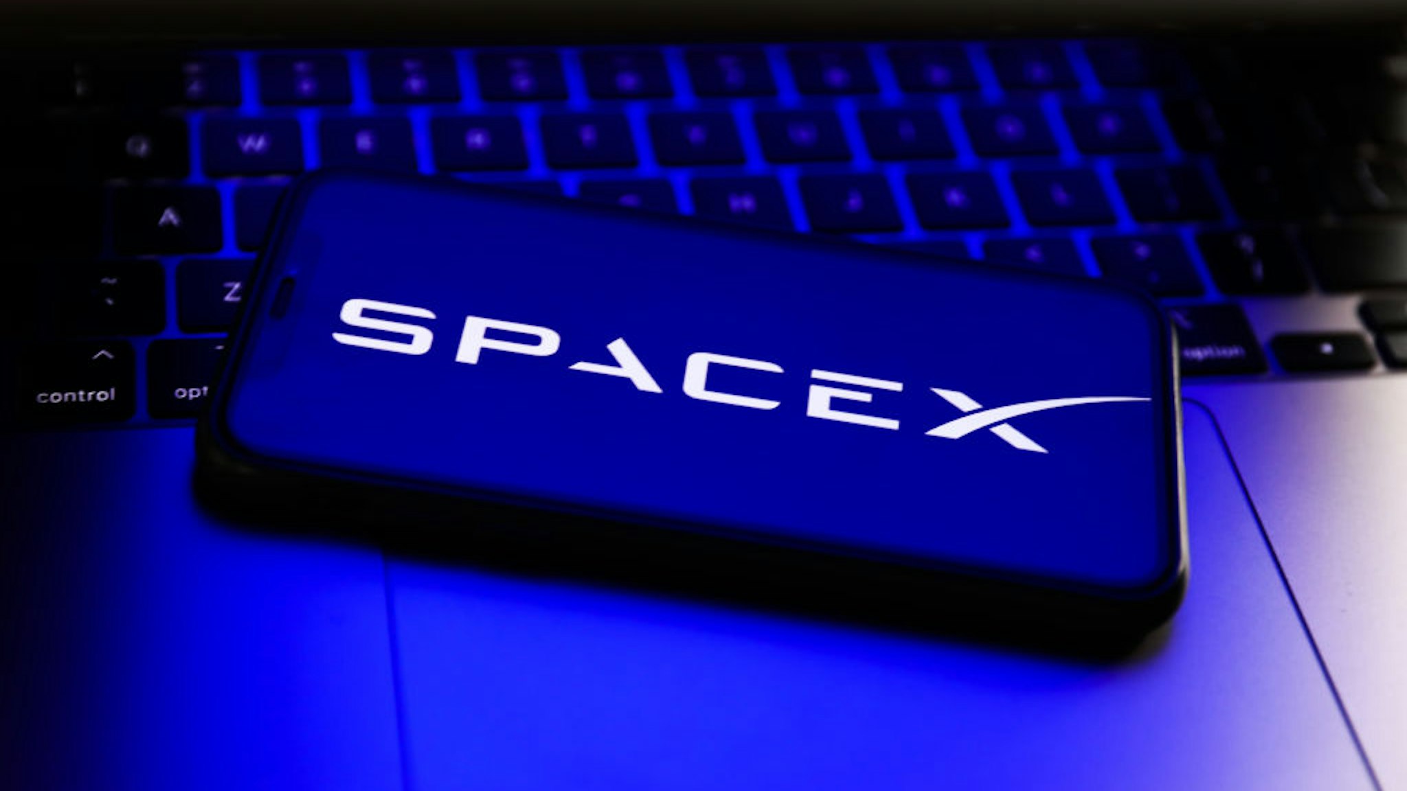 SpaceX logo displayed on a phone screen and a laptop keyboard are seen in this illustration photo taken in Poland on April 24, 2022. (Photo illustration by Jakub Porzycki/NurPhoto via Getty Images)