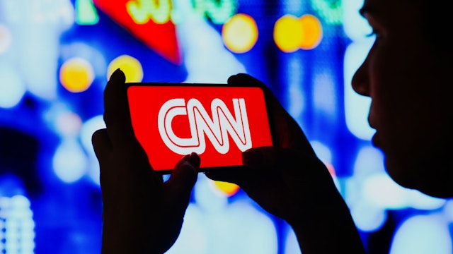 BRAZIL - 2022/06/06: In this photo illustration, a silhouetted woman holds a smartphone with the Cable News Network (CNN) logo displayed on the screen. (Photo Illustration by Rafael Henrique/SOPA Images/LightRocket via Getty Images)