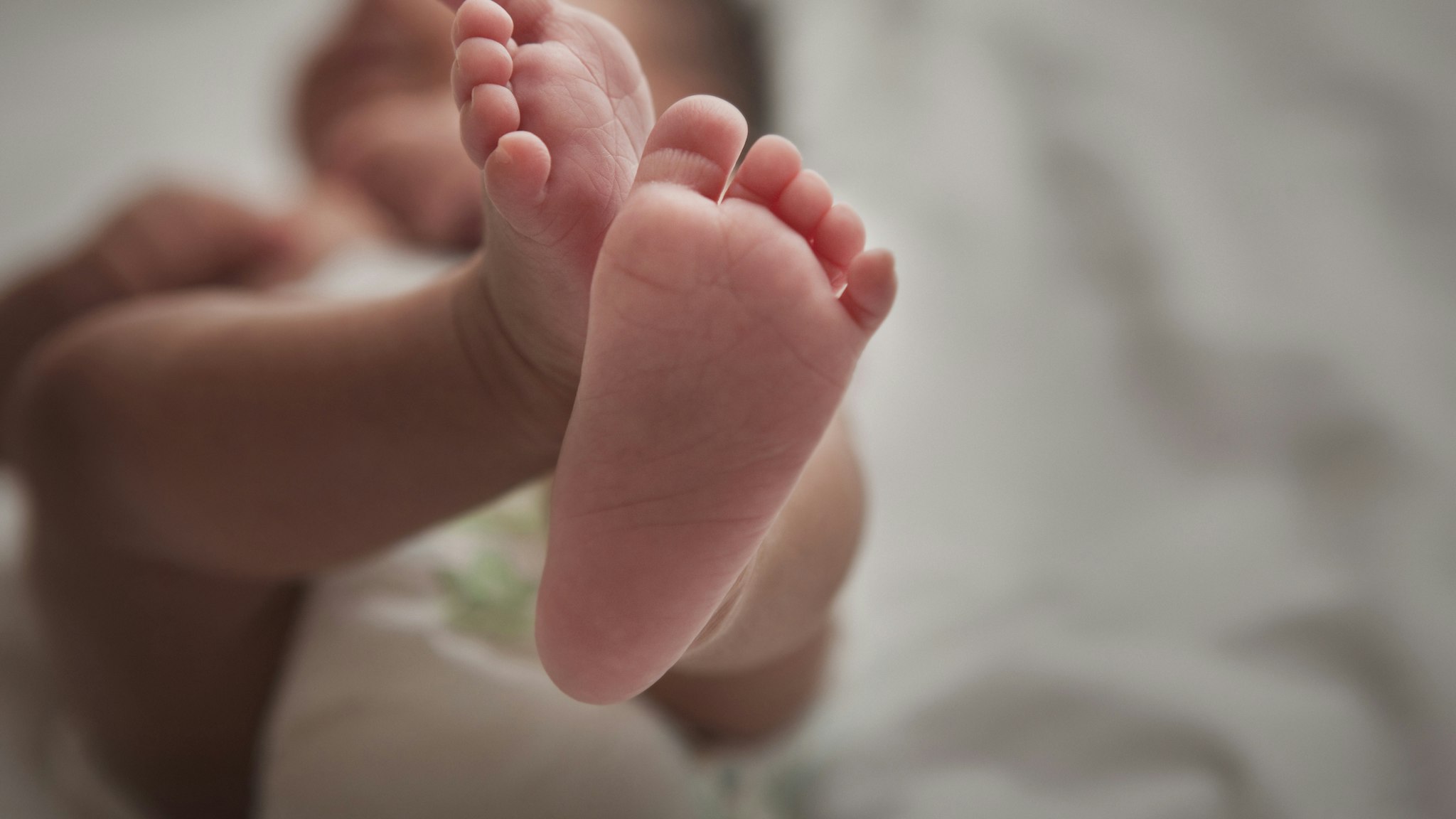 Close up of mixed race newborn baby girl's feet - stock photo