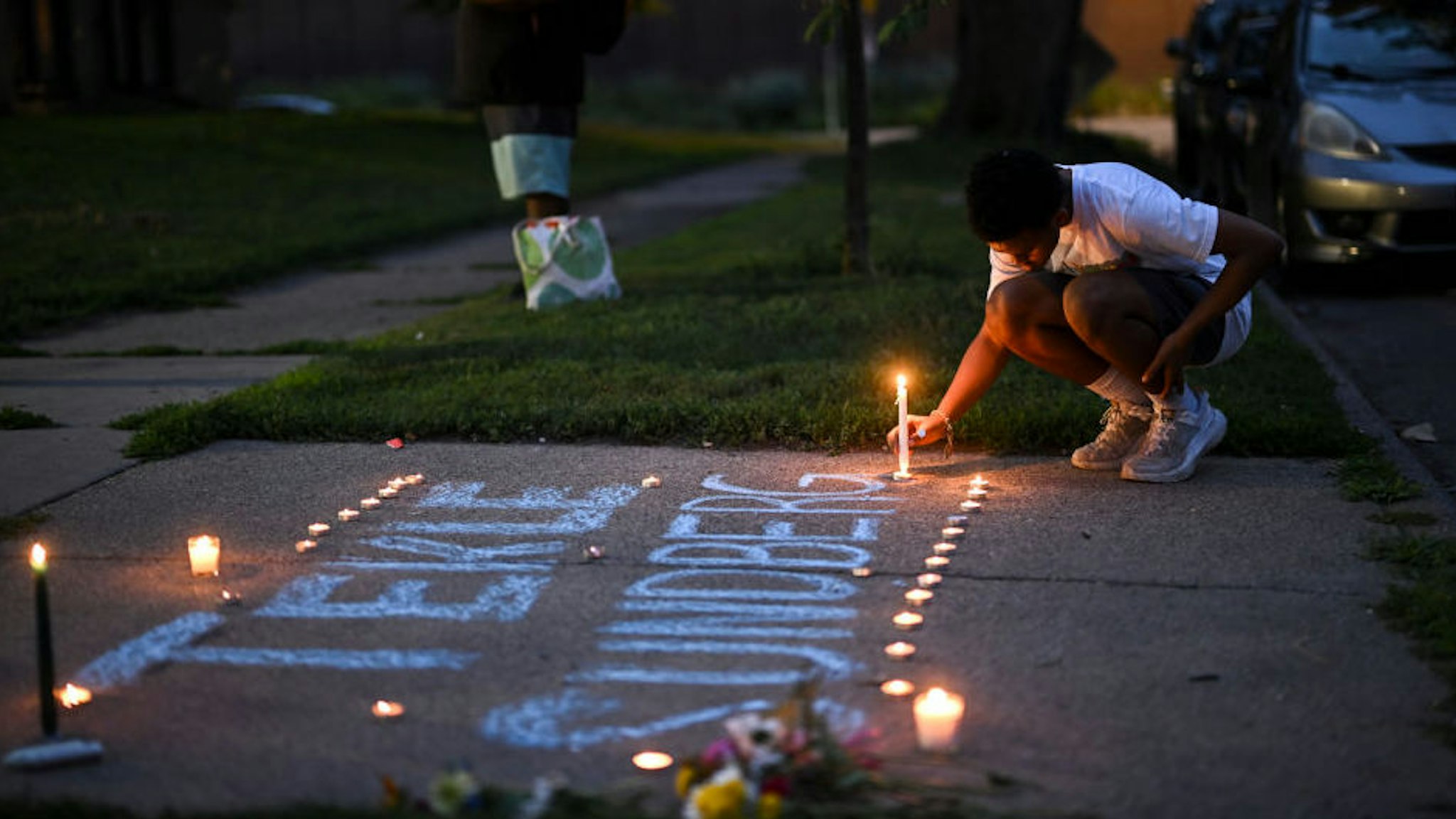 A mourner places a candle during a vigil for 20-year old Andrews Tekle Sunberg Thursday, July 14, 2022 outside the apartment building where he was killed by Minneapolis Police in Minneapolis, Minn..
