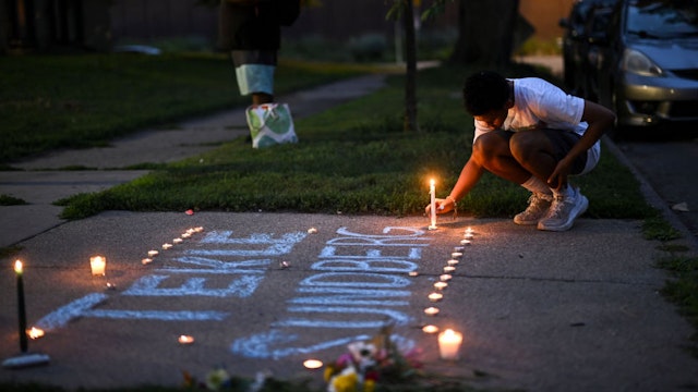 A mourner places a candle during a vigil for 20-year old Andrews Tekle Sunberg Thursday, July 14, 2022 outside the apartment building where he was killed by Minneapolis Police in Minneapolis, Minn..