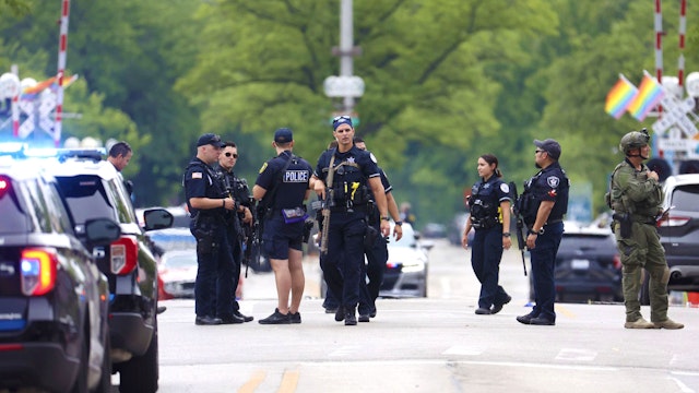 Law enforcement officials work the scene along the Highland Park Fourth of July parade route after people fled the scene on July 4, 2022, after a shooter fired on the Chicago suburb&apos;s Fourth of July parade.