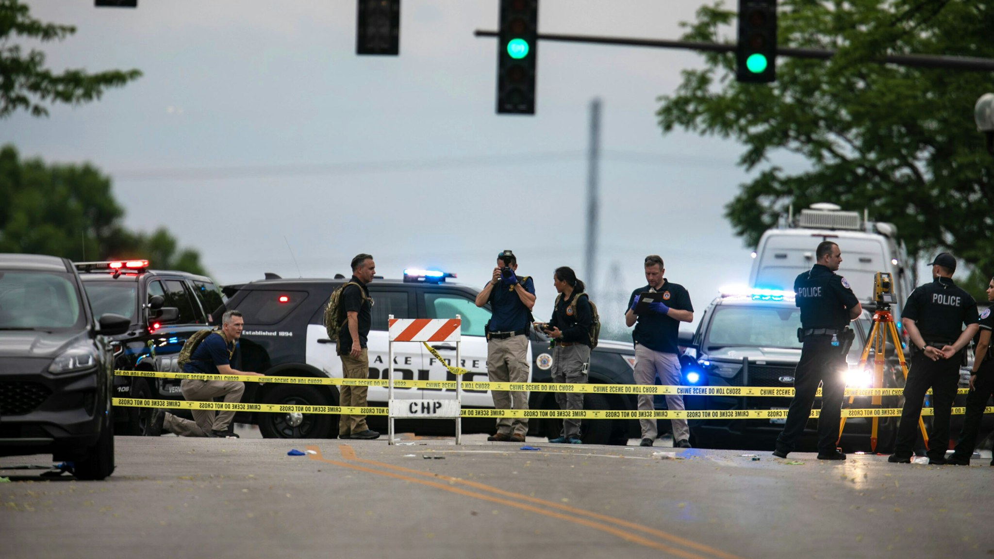 Police officers take photos and investigate at the scene of a mass shooting in Highland Park, Illinois, the United States, July 4, 2022. Six people have been confirmed killed in a mass shooting at an Independence Day parade Monday morning in Highland Park in the northern suburbs of Chicago, Illinois.