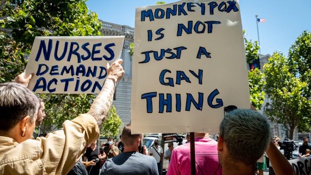 People hold signs during a rally to demand that the federal government respond quickly to the recent San Francisco monkeypox outbreak at the San Francisco Federal Building on July 18, 2022 in San Francisco, California.