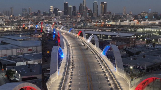 A drone view at dawn of the downtown skyline and the bridge arches majestically lit in red white and blue during the opening of the new 6th Street Bridge on July 10, 2022 in Los Angeles, California