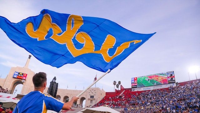 November 20: UCLA cheer team member rallies the crowd with the UCLA flag as the Bruins take a big lead over USC in the fourth quarter at Los Angeles Memorial Coliseum in Los Angeles on Saturday, Nov. 20, 2021.