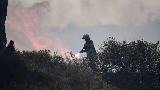 A firefighter works to put out a wildfire in Tarascon, southeastern France, on July 15, 2022.