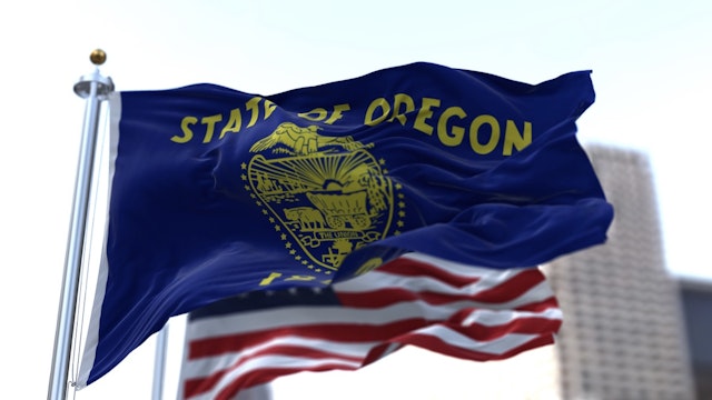 The flags of the Oregon state and United States waving in the wind - stock photo The flags of the Oregon state and United States waving in the wind. Democracy and independence. American state. rarrarorro via Getty Images