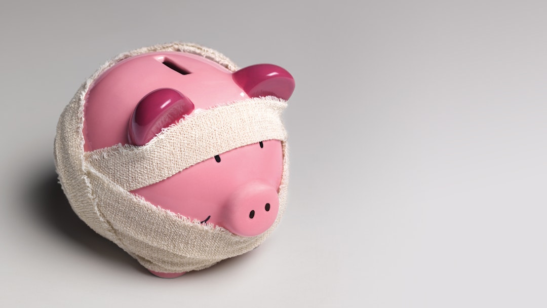 Ill piggy bank with bandages - stock photo