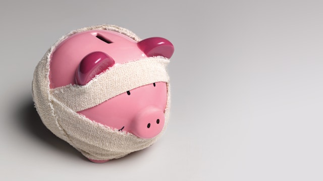 Ill piggy bank with bandages - stock photo