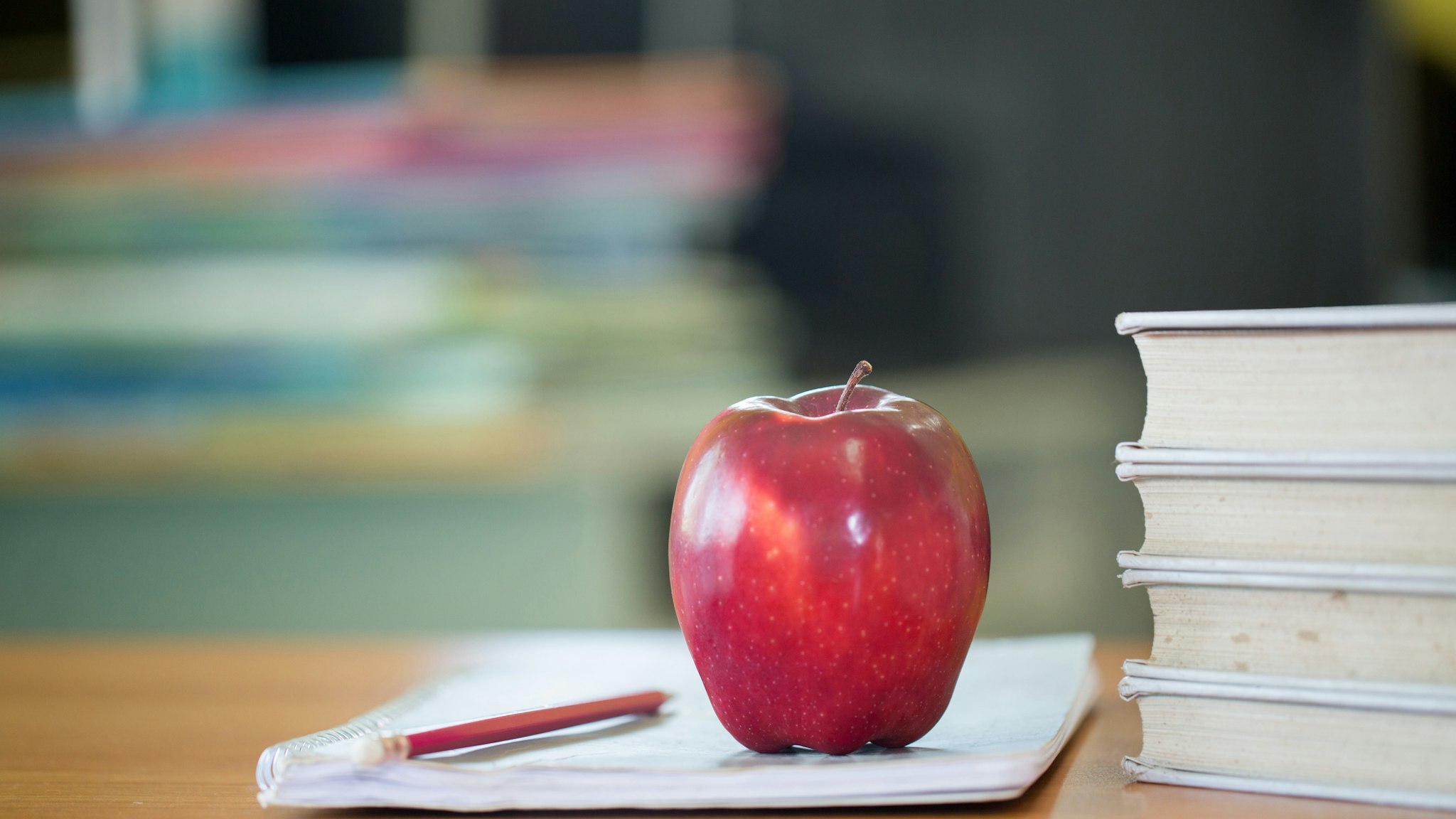 School teacher's desk with stack of books and apple, Educational concept. - stock photo
