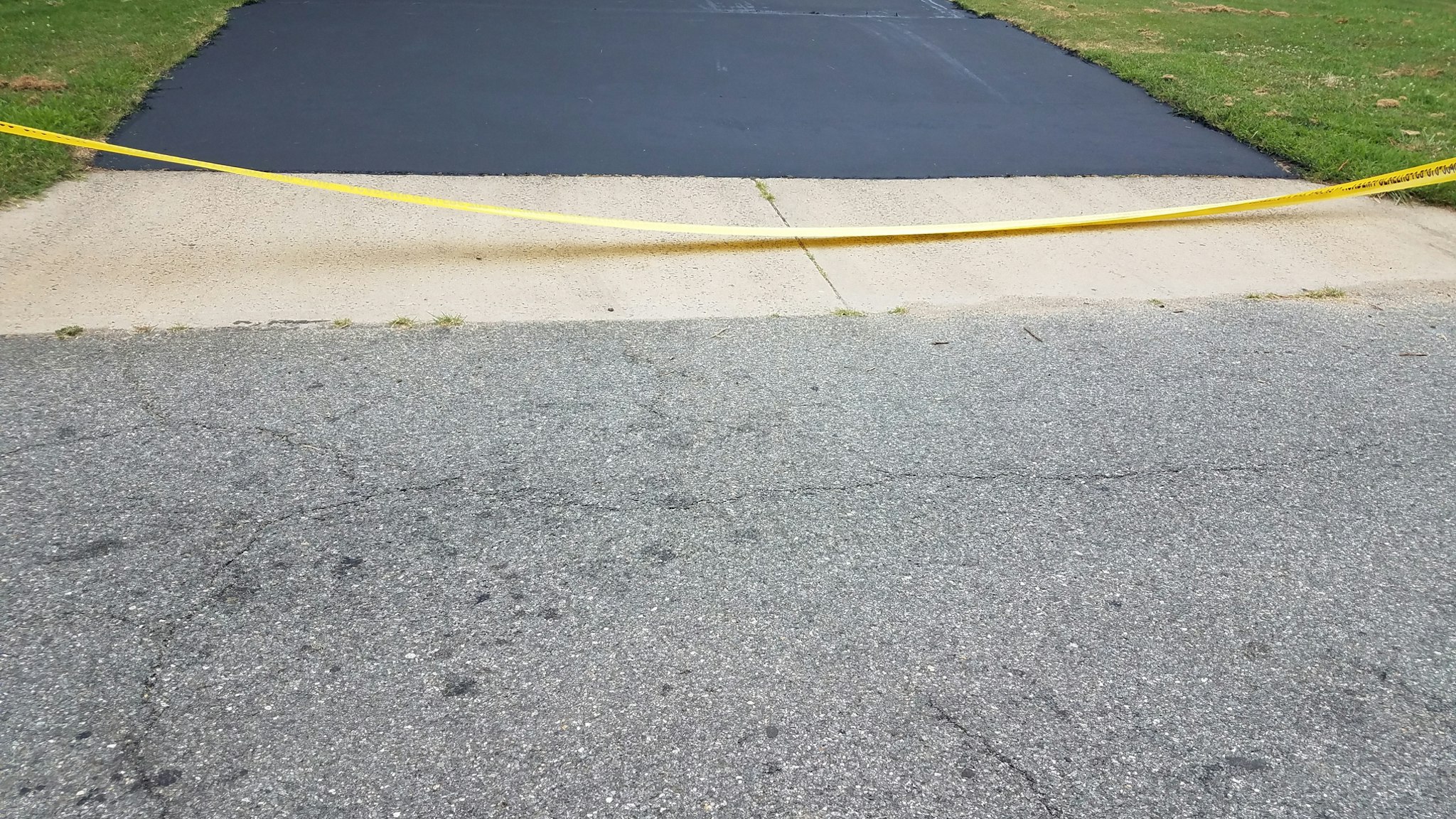 New asphalt driveway and yellow caution tape - stock photo