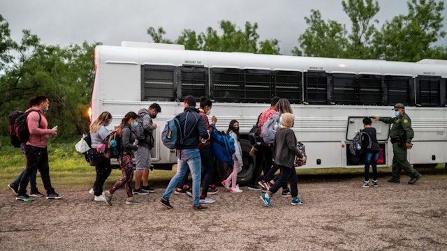 Migrants make their way toward a bus after being apprehended near the border between Mexico and the United States in Del Rio, Texas on May 16, 2021. - Crossings in Del Rio have risen significantly this year with many crossings earlier this year by Haitian migrants and now many coming to seek asylum from Venezuela. (Photo by Sergio FLORES / AFP) (Photo by SERGIO FLORES/AFP via Getty Images)