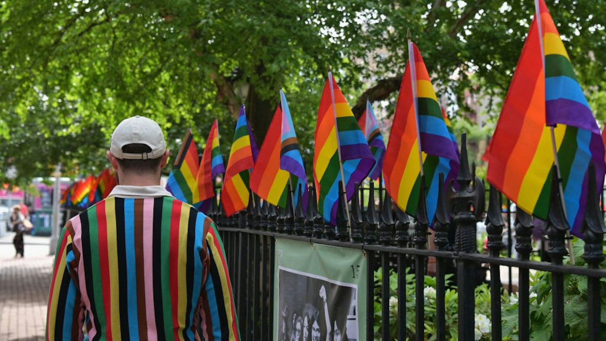 A person wearing a sweater with 'Progress Pride Flag' colors, including rainbow and black and brown stripes for communities of color, walks past rainbow flags at the Stonewall National Monument, the first US national monument dedicated to LGBTQ history and rights, marking the birthplace of the modern lesbian, gay, bisexual, transgender, and queer civil rights movement, on June 1, 2020 in New York City. (Photo by Angela Weiss / AFP) (Photo by ANGELA WEISS/AFP via Getty Images)