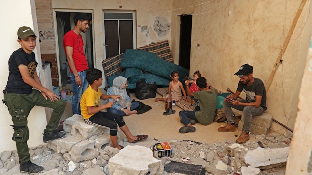 Wissam Joudeh (R) sits with his family in his partially destroyed house in Rafah in the southern Gaza Strip on August 9, 2022 following the latest round of fighting between Israel and Palestinian militants. - An Egypt-brokered ceasefire reached late on August 7 ended the intense fighting that killed 46 people including 16 children and wounded 360 in the enclave, according to Gaza's health ministry, updating an earlier toll of 44.