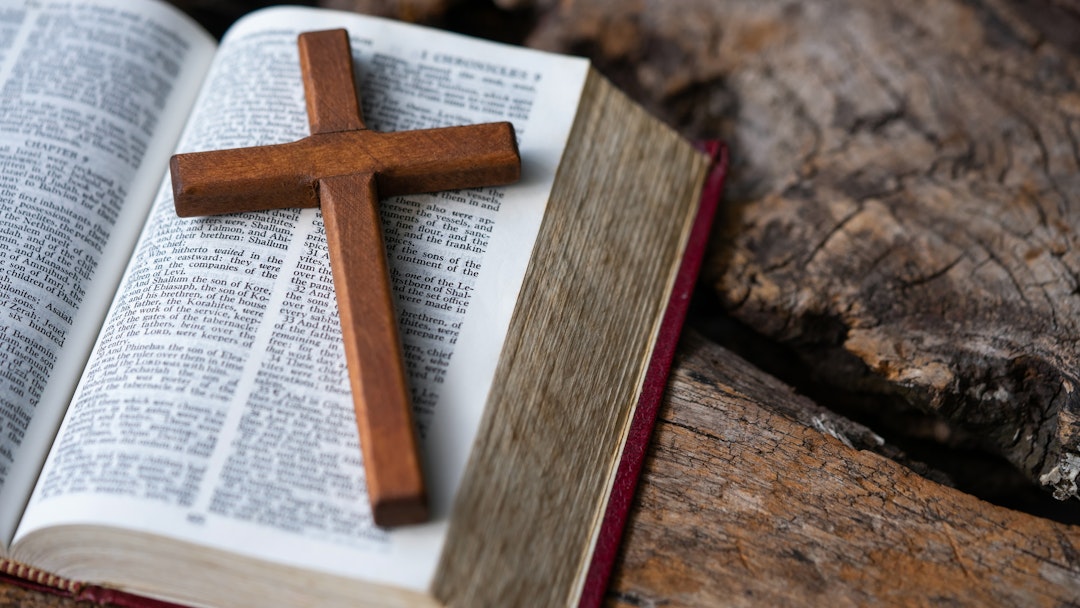Wooden cross, Holy Bible on table