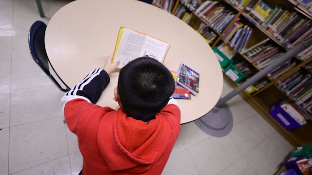 NEW YORK, NEW YORK - FEBRUARY 02: A student in the library reads a book after receiving candy and a red envelope in a cultural celebration of the Lunar New Year at Yung Wing School P.S. 124 on February 02, 2022 in New York City. NYC schools were closed yesterday in observance of what is considered the most important day in the Chinese calendar with the start of the New Year. This event is not only relevant in Asia, but also in other countries where this Chinese tradition is respected and celebrated and is on the table to become the next US Federal Holiday. (Photo by Michael Loccisano/Getty Images)