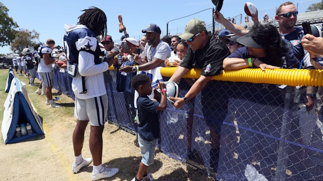 Trevon Diggs #7 of the Dallas Cowboys and son Aaiden sign autographs during training camp at River Ridge Fields on August 08, 2022 in Oxnard, California.