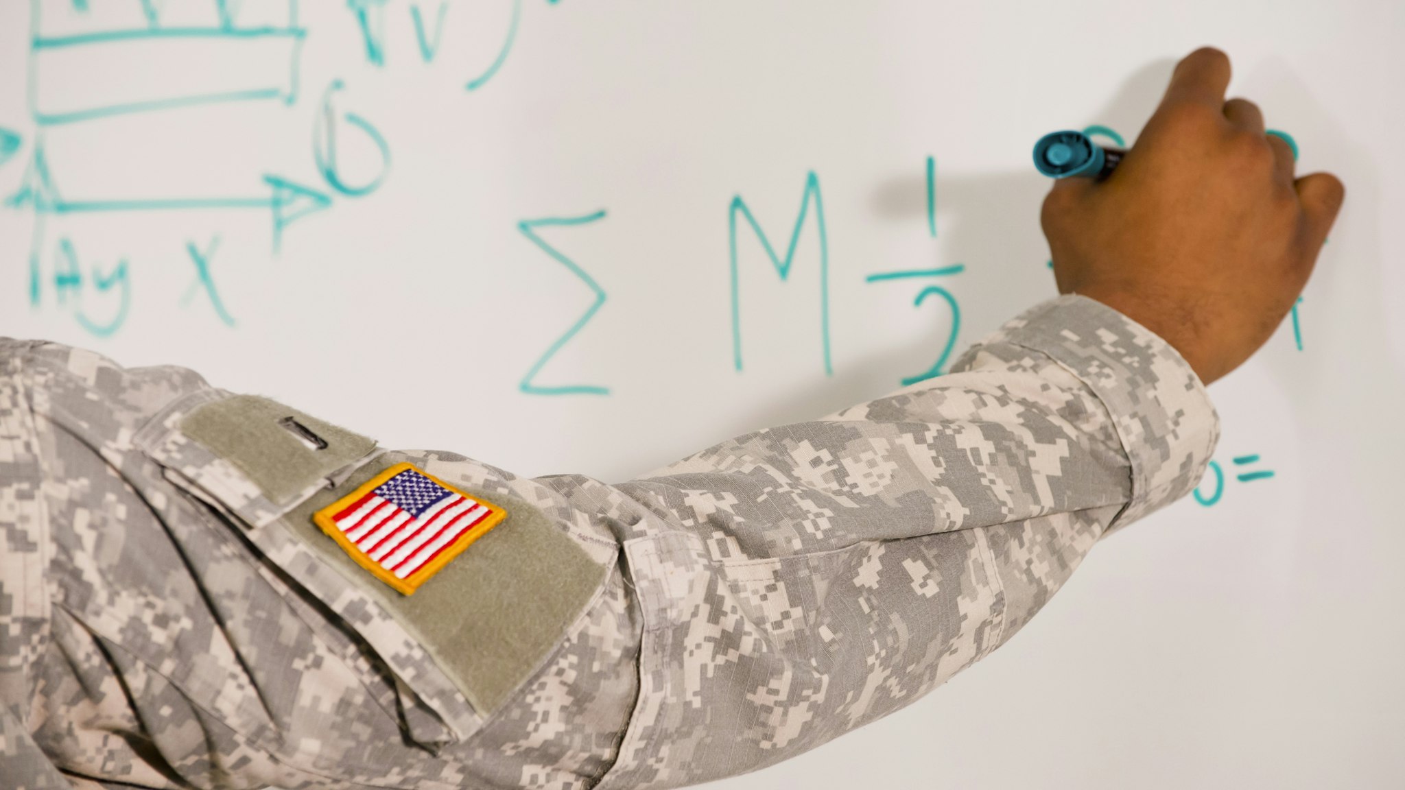 Black soldier writing on whiteboard