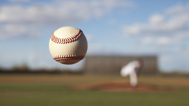 The dancing knuckleball pitch slowly approaches the plate in the summer sport of Baseball.