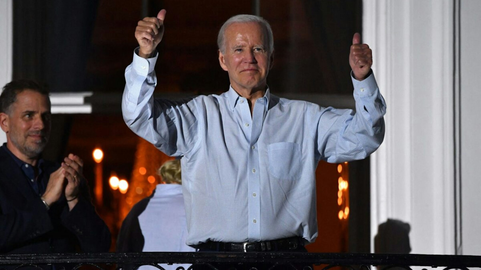 US President Joe Biden gives two thumbs up from a balcony of the White House as his son Hunter Biden (L) looks on during 4th of July fireworks in Washington, DC, July 4, 2022.