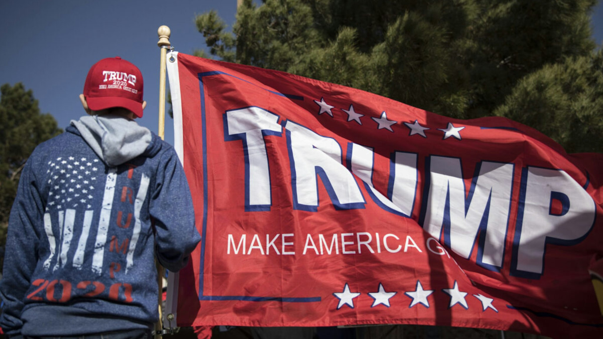 A boy holds a Trump flag at a rally for U.S. President Donald Trump in El Paso, Texas, U.S., on Monday, Feb. 11, 2019. Trump and prospective Democratic challenger Beto O'Rourke took part in dueling rallies in Texas on Monday, with each using the president's proposed border wall as an early proxy for the 2020 election