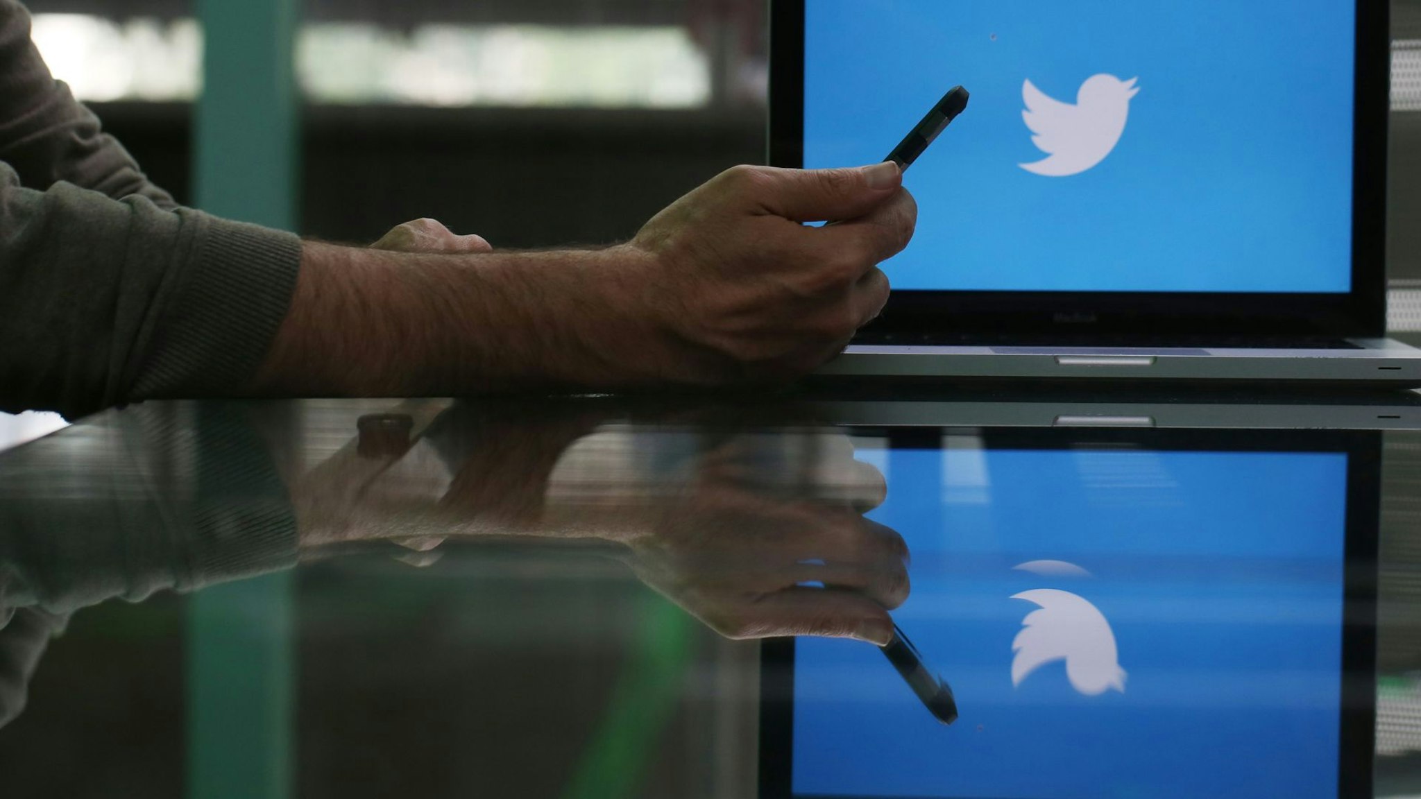 An Apple Inc. iPhone 6 smartphone is held as a laptop screen shows the Twitter Inc. logo in this arranged photograph taken in London, U.K., on Friday, May, 15, 2015.