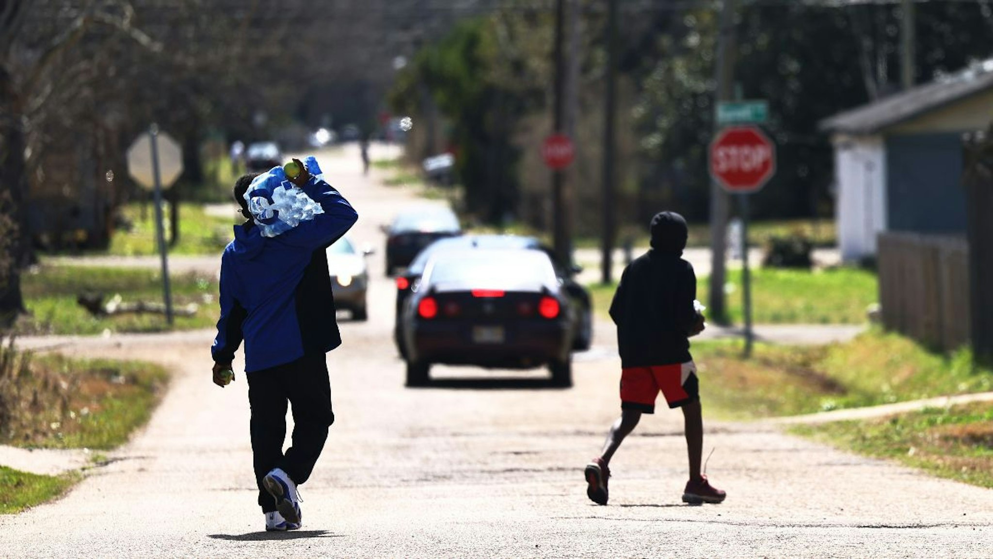 A man carries a case of water after receiving it at a water and food distribution drive held by College Hill Baptist Church and the World Central kitchen on March 07, 2021 in Jackson, Mississippi.