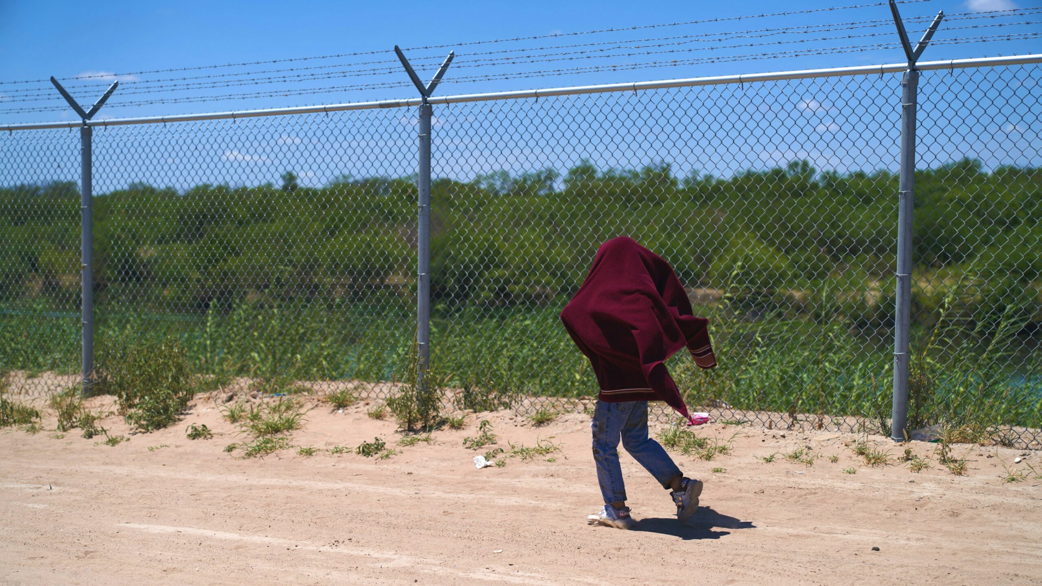 TEXAS, UNITED STATES - JULY 26: A migrant child walks by a fence towards U.S. Border Patrol after illegally crossing into Eagle Pass, Texas U.S. from Mexico on Tuesday July 26, 2022.